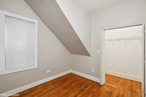 an empty room with wooden floor closet and windows
