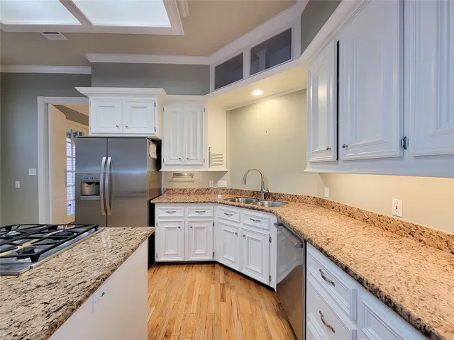 a kitchen with granite countertop a sink stainless steel appliances and cabinets