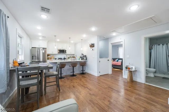 a kitchen with stainless steel appliances kitchen island granite countertop a table chairs sink and cabinets