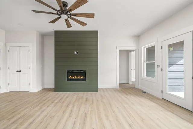 a view of empty room with wooden floor and fan