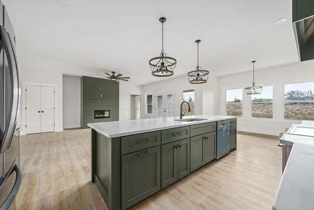 a kitchen with stainless steel appliances granite countertop cabinets a sink a window and chairs