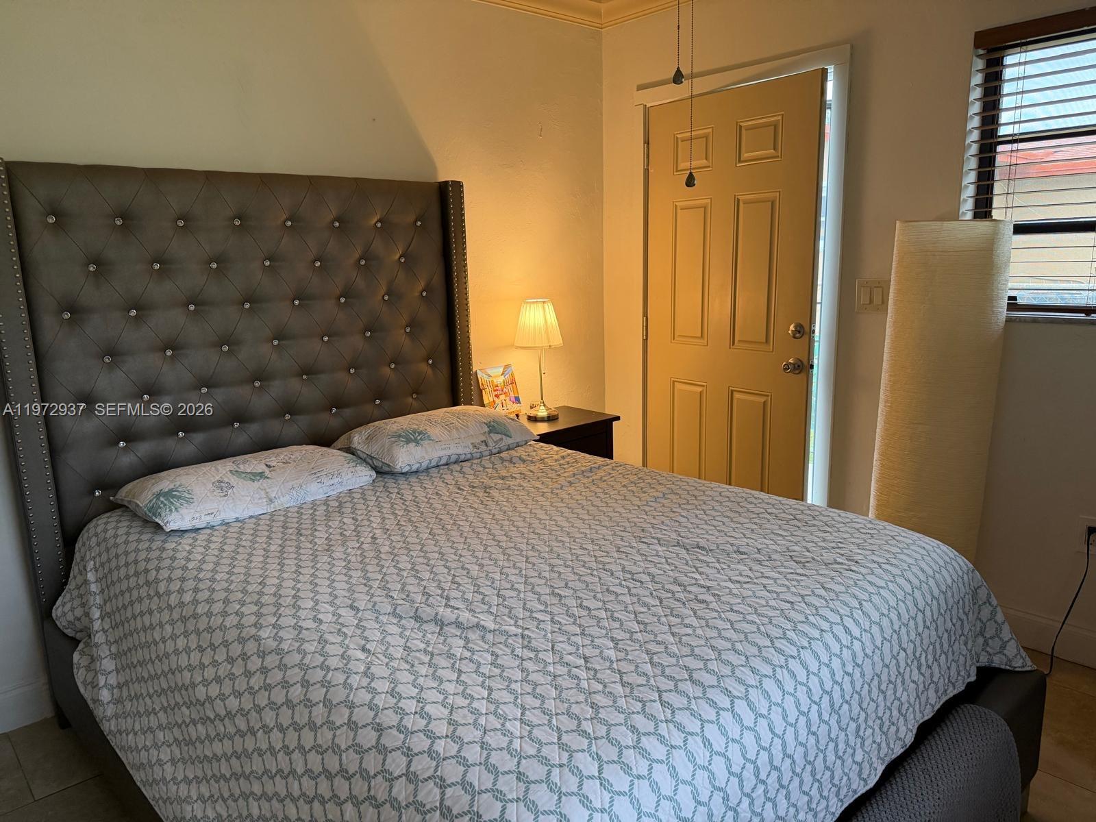 1350 Northwest 96th Street, Unit 2 Miami, FL 33147 - Photo 11 of 12 a bedroom with a bed and a black white checkered curtain