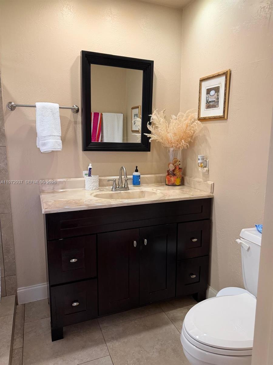 1350 Northwest 96th Street, Unit 2 Miami, FL 33147 - Photo 3 of 12 a bathroom with a toilet a sink and mirror