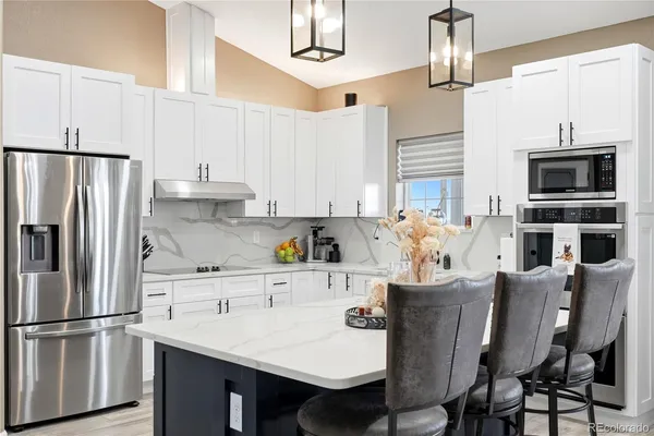 a kitchen with stainless steel appliances a dining table chairs refrigerator and cabinets