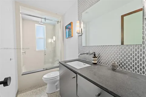 a bathroom with a granite countertop sink a toilet and shower