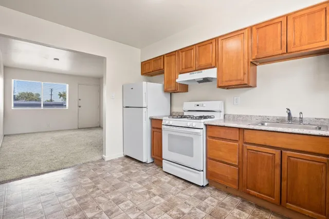 a kitchen with granite countertop a sink cabinets stainless steel appliances and a window