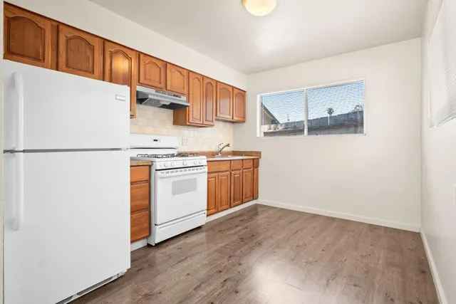 a kitchen with a white cabinets and wooden floor