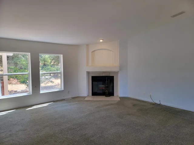 en empty room with windows and fireplace