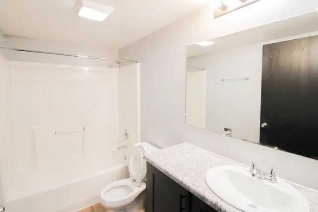 a bathroom with a granite countertop sink toilet a mirror and shower