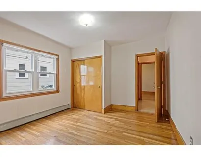 a view of an empty room with window and wooden floor