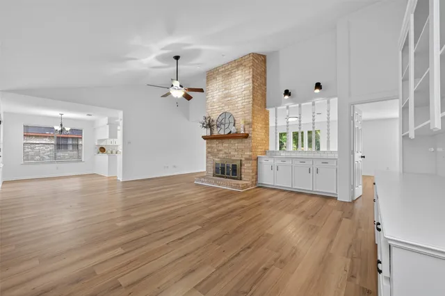 a view of a kitchen and an empty room with wooden floor