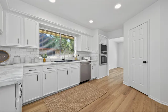 a kitchen with granite countertop a sink cabinets stainless steel appliances and a window