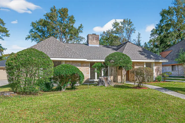 a view of a house with a yard and a large tree