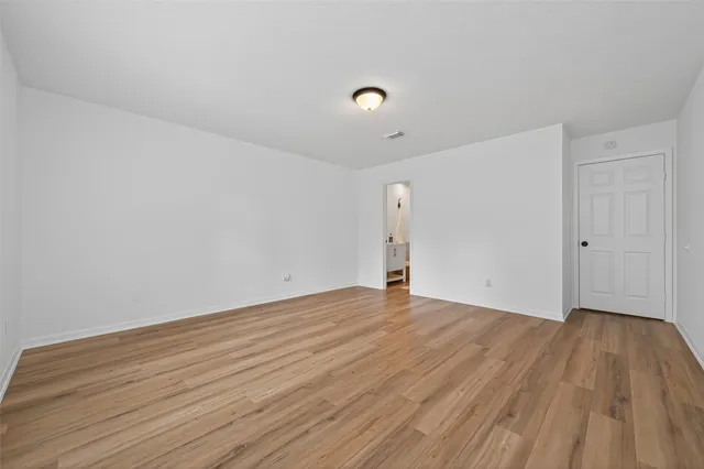 a view of an empty room with wooden floor and a sink