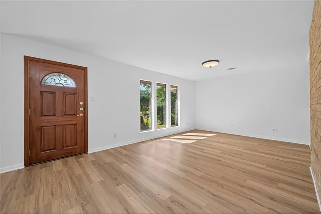 a view of an empty room with a window and wooden floor