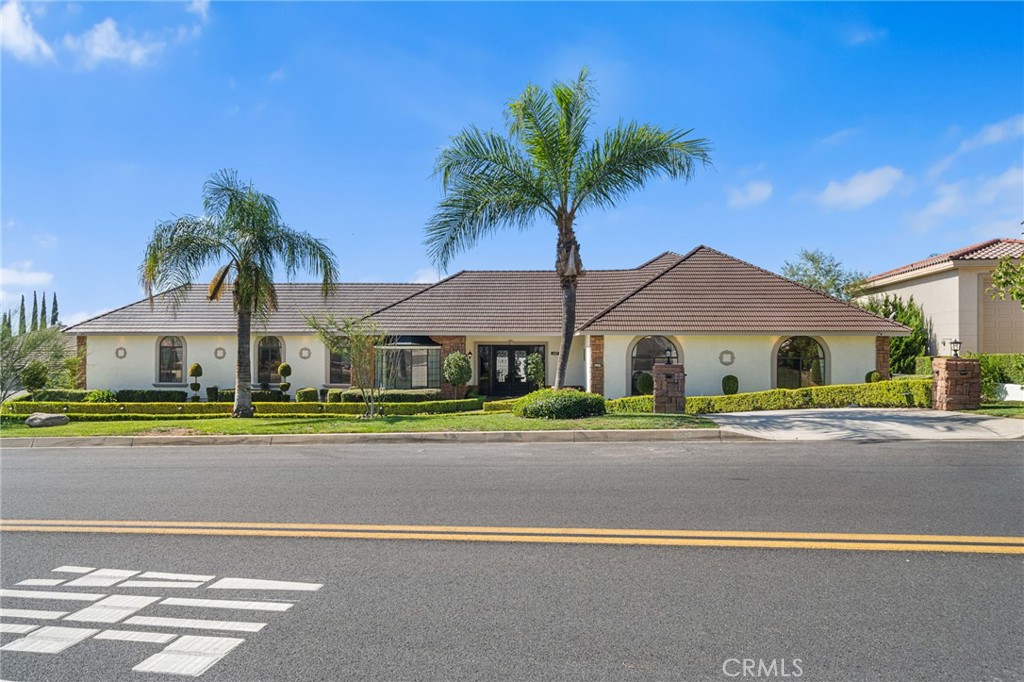 front view of house with a yard and palm trees