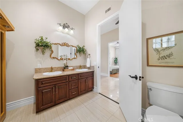a spacious bathroom with a granite countertop sink a toilet a mirror and shower