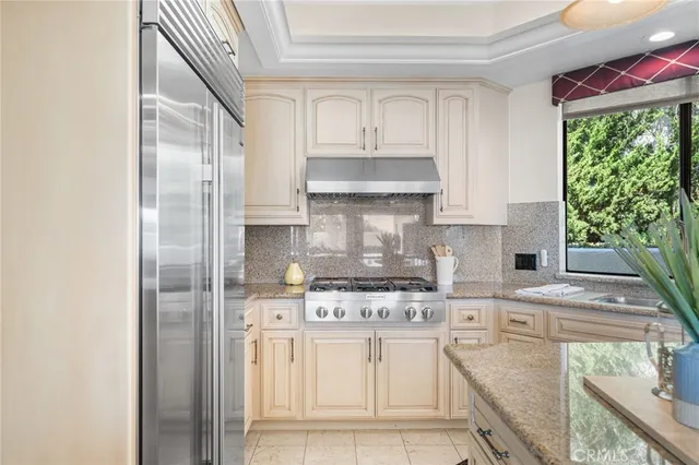 a kitchen with stainless steel appliances granite countertop a stove a sink and white cabinets