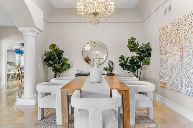 a view of a dining room with furniture a potted plant and a chandelier