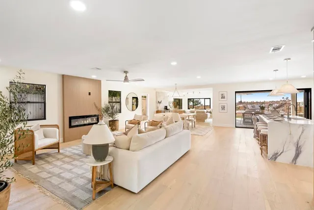 a living room with furniture kitchen view and a large window