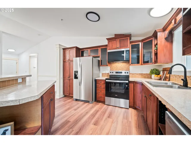 a kitchen with stainless steel appliances granite countertop a refrigerator a stove and a sink