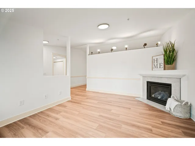 a view of an empty room with wooden floor and a fireplace