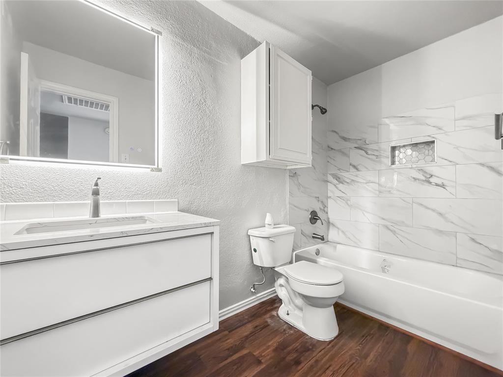 5840 Spring Valley Road, Unit 1104 Dallas, TX 75254 - Photo 4 of 16 Bathroom featuring a floating vanity with integrated sink, illuminated mirror, and wood-finish flooring