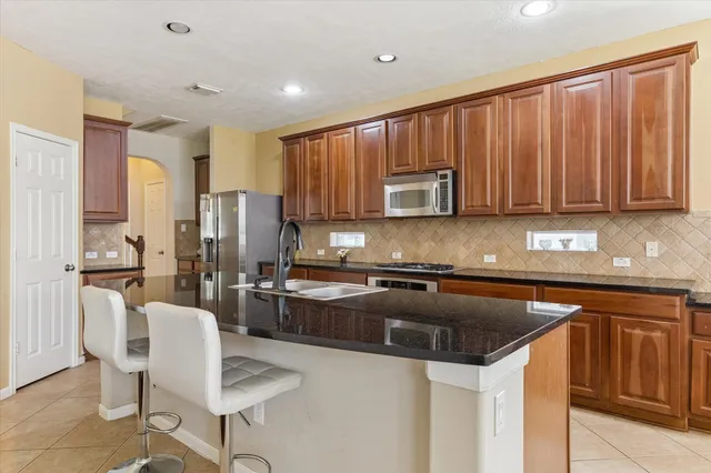 a kitchen with kitchen island granite countertop wooden cabinets and stainless steel appliances