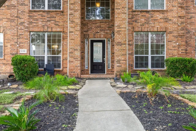 a front view of a brick house with a yard and plants