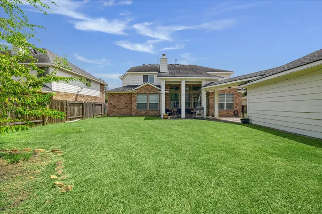 a view of a white house that has a small yard and large trees