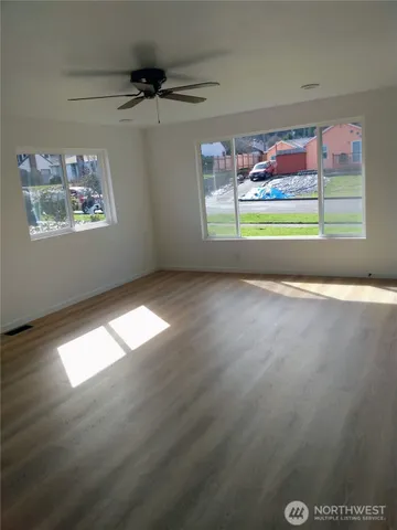 an empty room with windows and fan