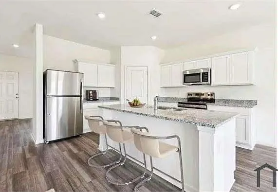 a kitchen with stainless steel appliances granite countertop a refrigerator a stove a sink a stove a dining table and chairs