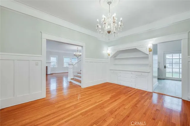a empty room with wooden floor chandelier and windows