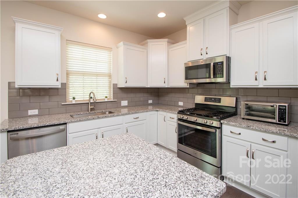 820 Ruckers Court Tega Cay, SC 29708 - Photo 11 of 46 a kitchen with stainless steel appliances granite countertop a stove a sink and a microwave