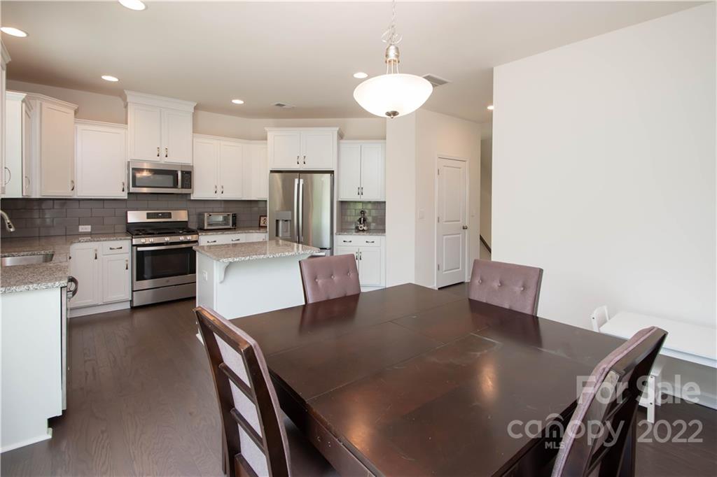 820 Ruckers Court Tega Cay, SC 29708 - Photo 15 of 46 a kitchen with stainless steel appliances granite countertop a stove a refrigerator a sink a dining table and chairs