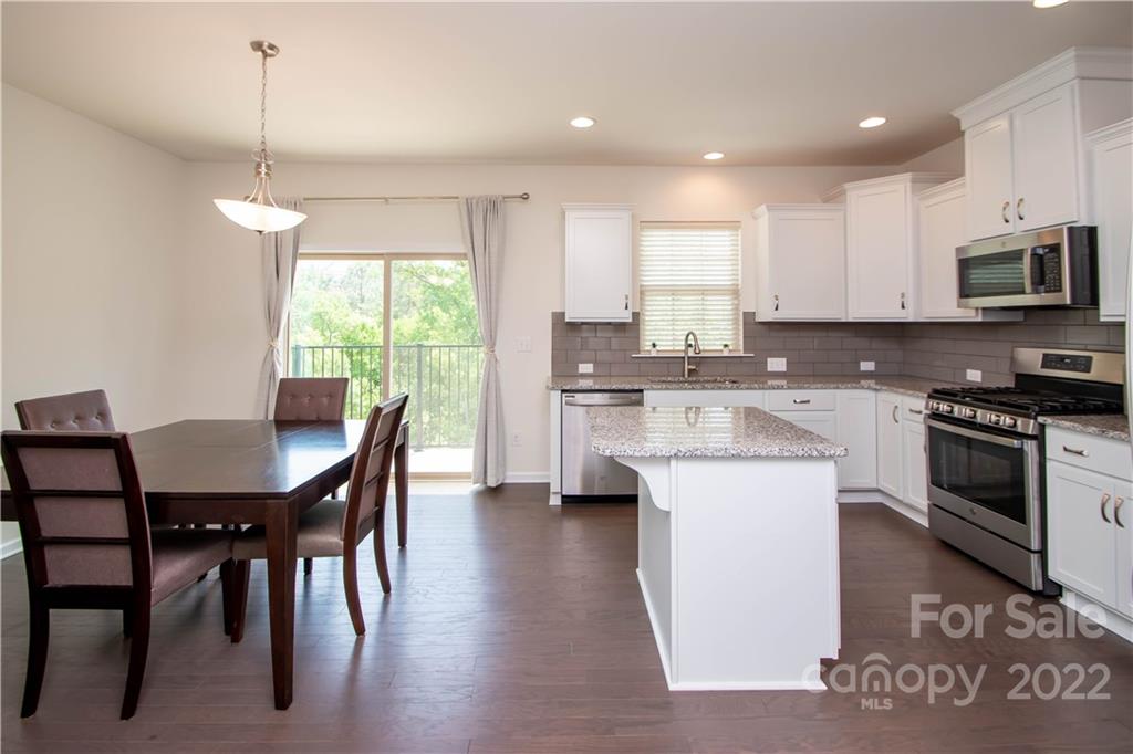 820 Ruckers Court Tega Cay, SC 29708 - Photo 10 of 46 a kitchen with stainless steel appliances kitchen island granite countertop a stove a sink a microwave a dining table and chairs