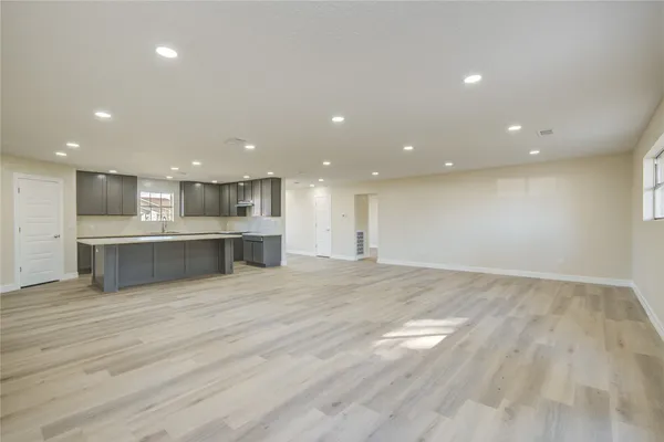 a view of an empty room with kitchen and a window