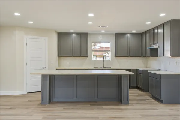 a kitchen with a sink cabinets and wooden floor