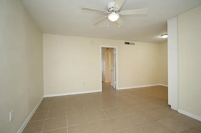 an empty room with a ceiling fan and a glass door