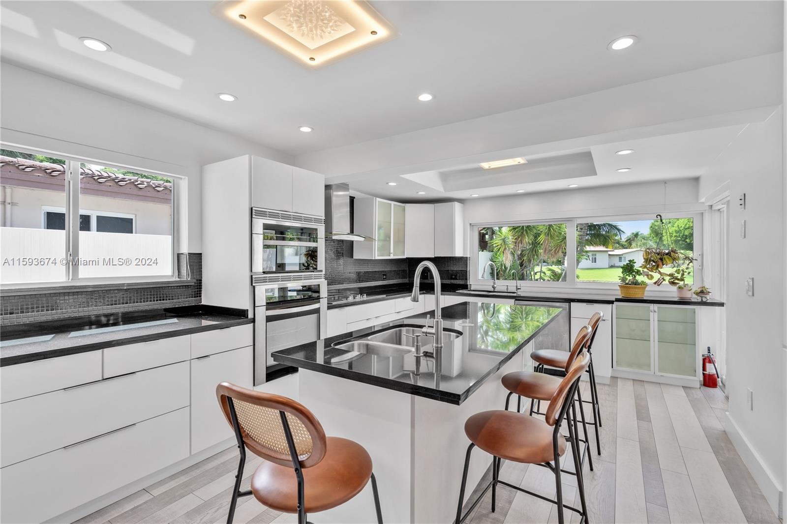 6341 Lake June Road Miami Lakes, FL 33014 - Photo 12 of 55 a kitchen with stainless steel appliances granite countertop a stove top oven a sink a dining table and chairs with wooden floor