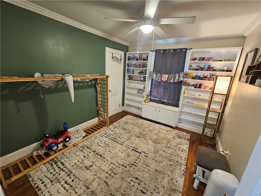 237 Pine Lane Anderson, SC 29621 - Photo 19 of 23 This cozy bedroom offers versatile built-in shelving, hardwood flooring, and a ceiling fan for comfort.