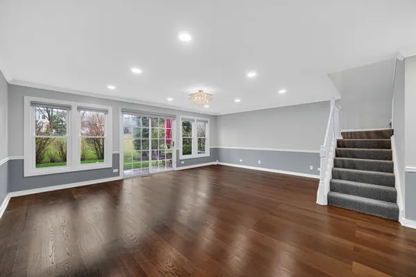 a view of an empty room with wooden floor and windows