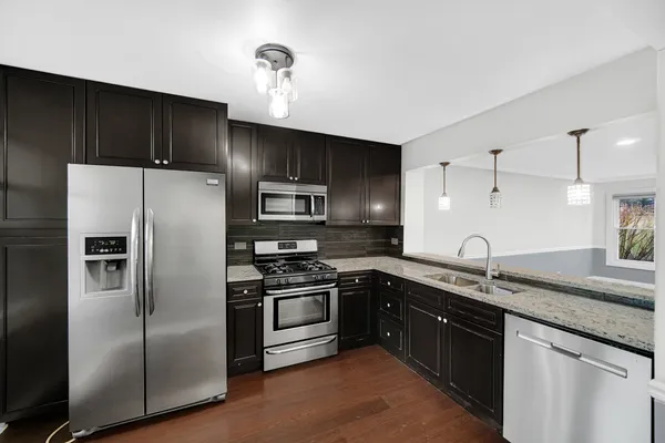 a kitchen with stainless steel appliances granite countertop a sink stove and refrigerator