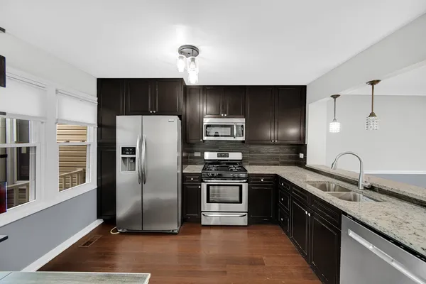 a kitchen with stainless steel appliances granite countertop a sink a stove and a refrigerator