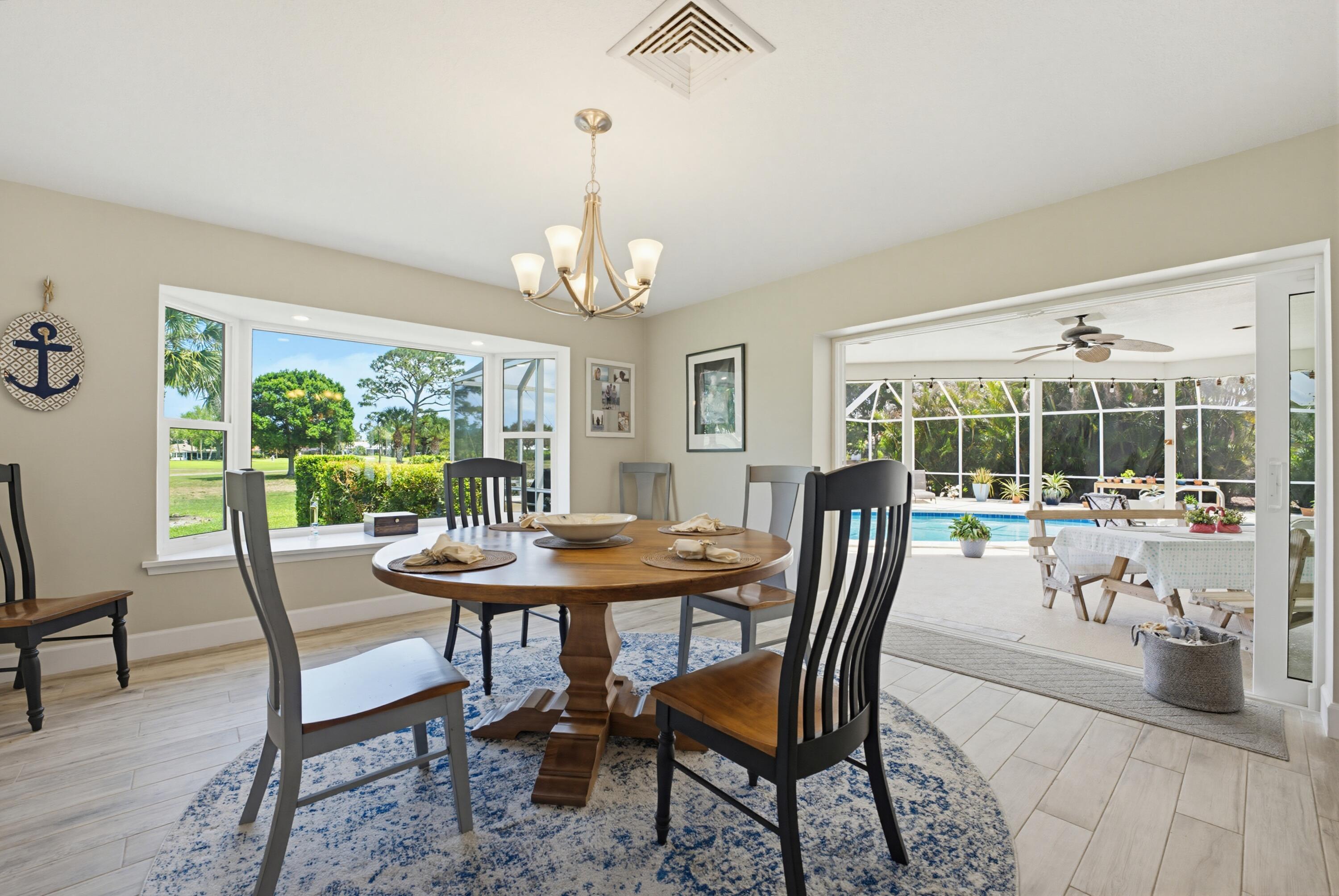 3491 Southeast Clubhouse Place Stuart, FL 34997 - Photo 17 of 43 a view of a dining room with furniture wooden floor and chandelier