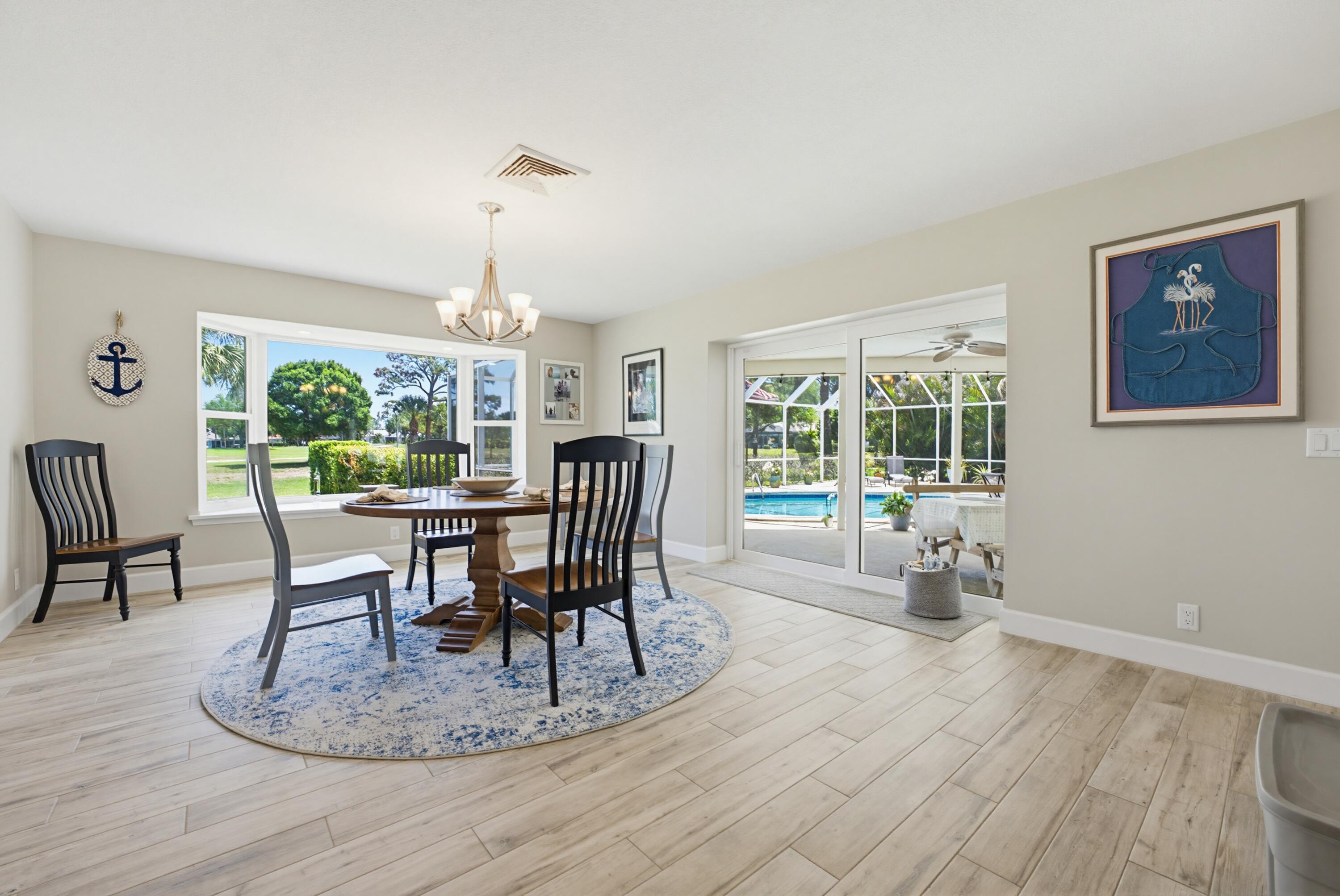 3491 Southeast Clubhouse Place Stuart, FL 34997 - Photo 23 of 43 a dining room with furniture a chandelier and wooden floor