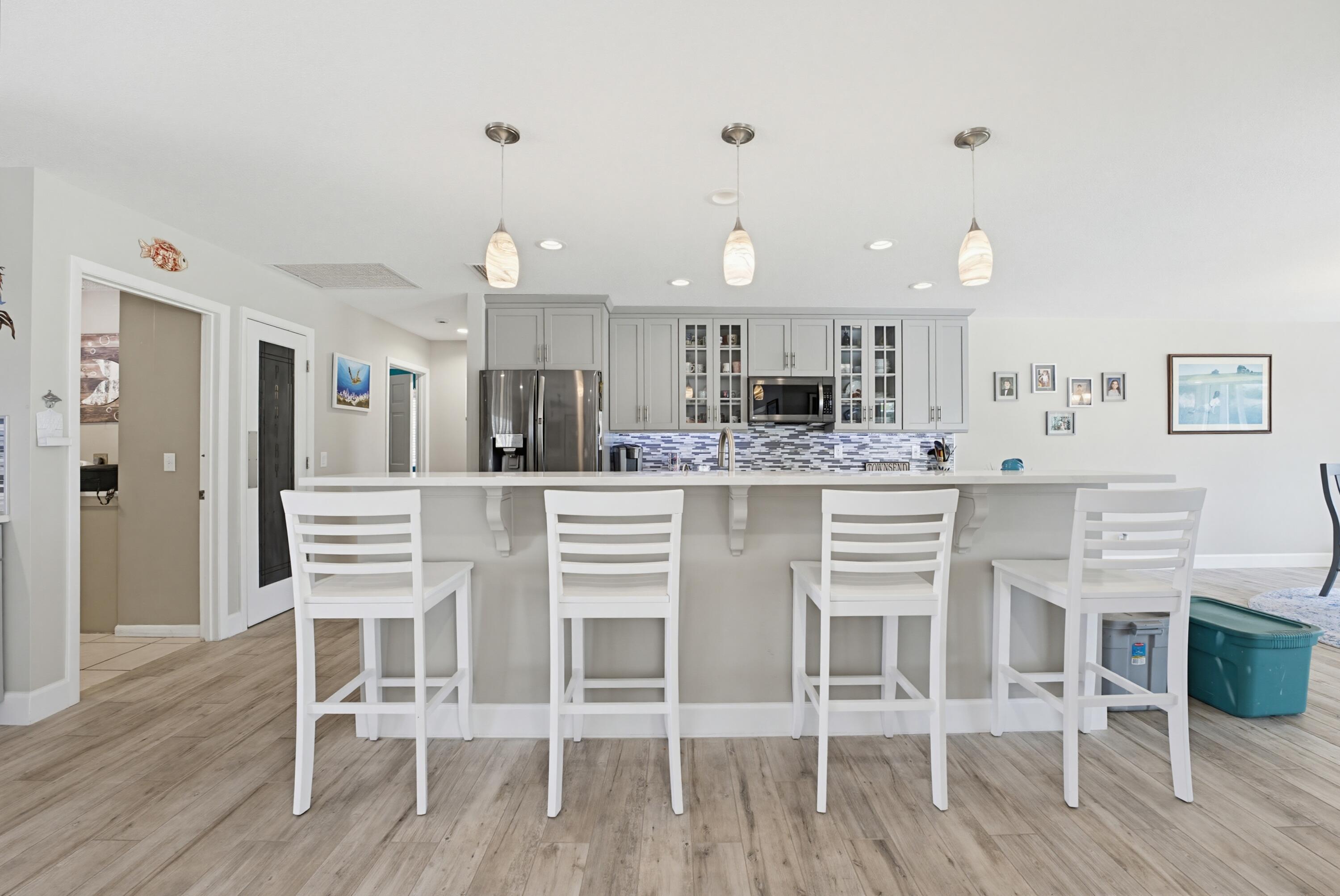 3491 Southeast Clubhouse Place Stuart, FL 34997 - Photo 4 of 43 a kitchen with stainless steel appliances kitchen island granite countertop a wooden floor and white cabinets