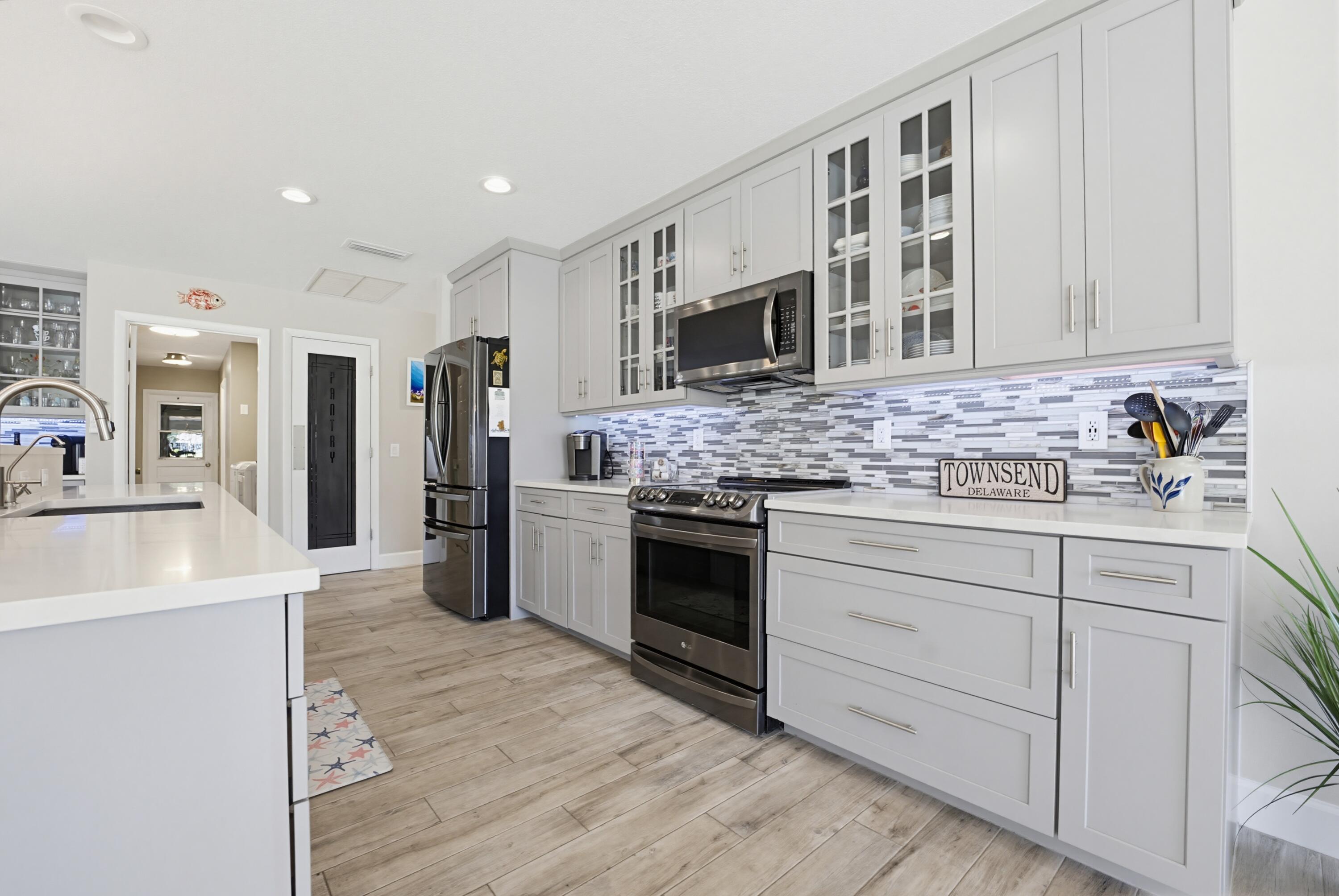 3491 Southeast Clubhouse Place Stuart, FL 34997 - Photo 6 of 43 a kitchen with stainless steel appliances kitchen island granite countertop a stove top oven a sink and dishwasher a refrigerator with wooden floor