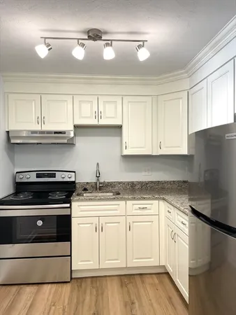 a kitchen with granite countertop white cabinets and stainless steel appliances