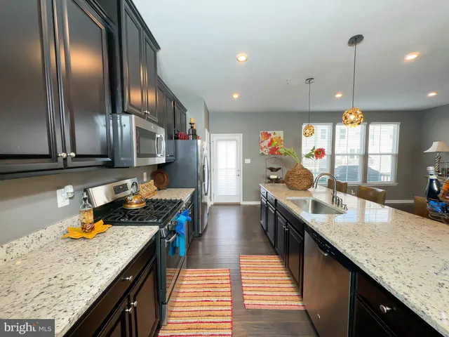 a kitchen with stainless steel appliances granite countertop sink stove top oven and refrigerator